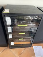 Front view showing black wood cabinet with glass door and interior shelves