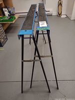 Two blue/black Mastercraft metal folding sawhorses standing side by side