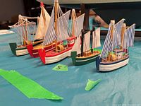 Group view of five small sailboat models on tabletop