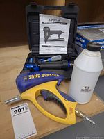 Overall view of stapler in case with manual, sand blaster gun, and sand bottle