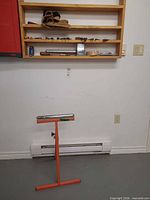 Roller stand front view with shelf holding hand tools and tool belt