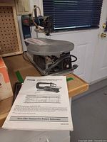 Ryobi SC162VS scroll saw on workbench with manual and book visible