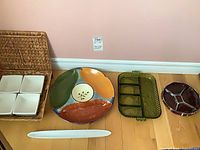 all nine pieces arranged: wicker tray with four dishes, hand-painted platter, green glass dish, brown dish, white olive tray