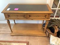 Front view of wood console table showing inlaid top, drawer fronts, lower shelf