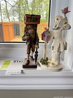 Both figurines side by side on windowsill