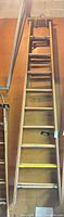 Full view of collapsed wood extension ladder leaning against wall