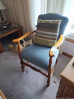 Front view of blue upholstered wooden armchair with striped pillow