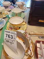 Multiple teacup and saucer sets showing variety of patterns and colours