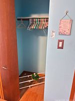 Closet interior showing assorted hangers on rod and metal three-tier shoe rack on floor