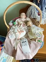 Both dolls inside wicker basket with pillow and blanket