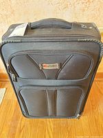 Front view of black Delsey softside carry-on with two front zip pockets and logo plate