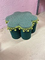 Angled view showing flower top, pom-pom trim, and cylindrical base