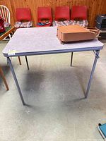 Overall view of gray folding table with laminate top and metal legs