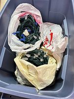 Two bags inside a tote containing bundled green-wire string lights