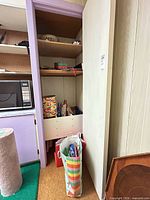 Closet shelf with rolls of wrapping paper, gift bags in striped carrier, metal tin on shelf