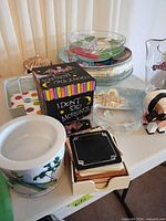 Overview of all items on table including pitcher, divided dish, Christmas tray, coaster set, ceramic crock, novelty box