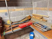 Overview of tools on shelf including socket set toolbox, panel saws, pry bars, hammers and wrenches