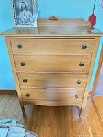 Front view showing four drawers, knobs, turned legs