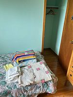 Stacked afghan, blanket, linens, doily and closet hangers