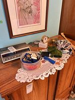 Top view of dresser showing GE clock radio, Avon alarm clock, container of keychains, velvet and satin pouches