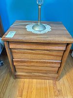 Front view of brown laminate nightstand showing three drawers and top surface