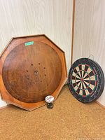 Crokinole board, dartboard and jar of discs grouped together