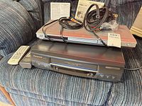 Both Panasonic units stacked with remotes, cables and manuals visible