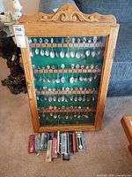 Full view of oak display cabinet with mounted souvenir spoons and boxed spoons at base