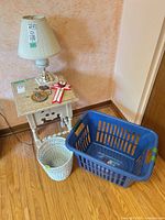 Overall view showing lamp on side table, blue laundry basket, white wicker basket, ribbon decor