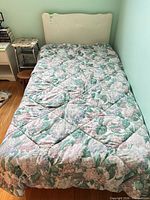 Twin bed with floral comforter and upholstered headboard
