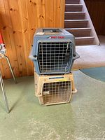 Front view of stacked gray-blue and tan Pet Taxi carriers showing metal doors and logos