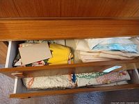 Drawer showing stacks of assorted folded vintage linens and crochet pieces