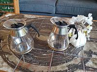 Both glass carafes on stands beside wedding cake topper