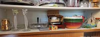 Shelf showing bowls, candlesticks, colored bowls stack, basket area