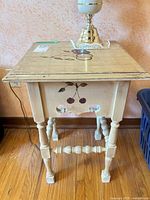 Full view front of cream square side table with fruit motif and turned legs