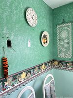 Overall shot showing clock, plaque, crochet hanging and duster on wall