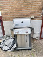 Front view of Weber Spirit grill with cover beside it