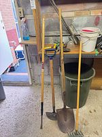 Group of long-handled tools, buckets, hooks, small tools on shelf