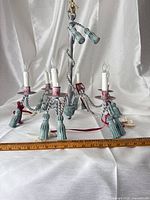 Chandelier laid horizontally showing five arms, tassels, faux candles and bird ornaments