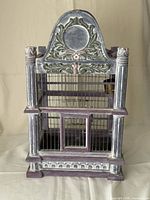 Front view showing ornate carved crest, column sides, front door, metal bars
