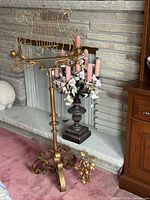 Full view of music stand, pedestal candelabra with candles and floral garland, and small wall sconce in front of fireplace