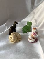 Four miniature cat figurines displayed on fabric background