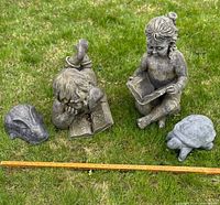 Group shot of four statues on grass with meter stick