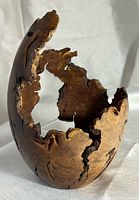 Front view of hollow burl wood sculpture showing live-edge opening and grain