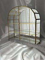 Full view of brass-tone glass curio cabinet with ruler showing width