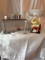 Group shot of entire lot showing bread box, scale with bowl and box, glass bottle, measuring cup, tart tins
