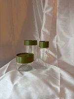 Front view of three Pyrex canisters showing size variation and olive lids