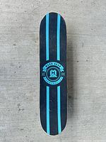 Grip side of skateboard showing blue and black stripes and Madd Gear logo