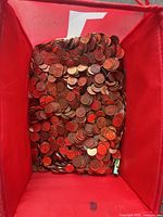 Top view of large quantity of loose pennies inside red bin
