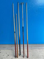 Five billiards items standing upright against blue wall